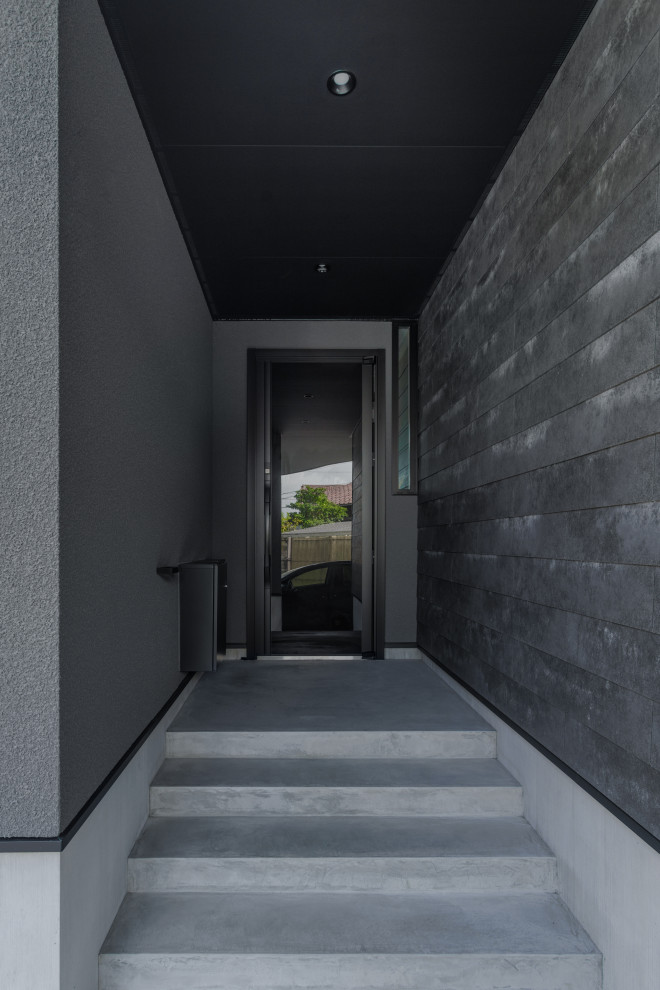 Foto de hall negro minimalista con paredes grises, suelo de cemento, puerta simple, puerta negra, machihembrado y boiserie