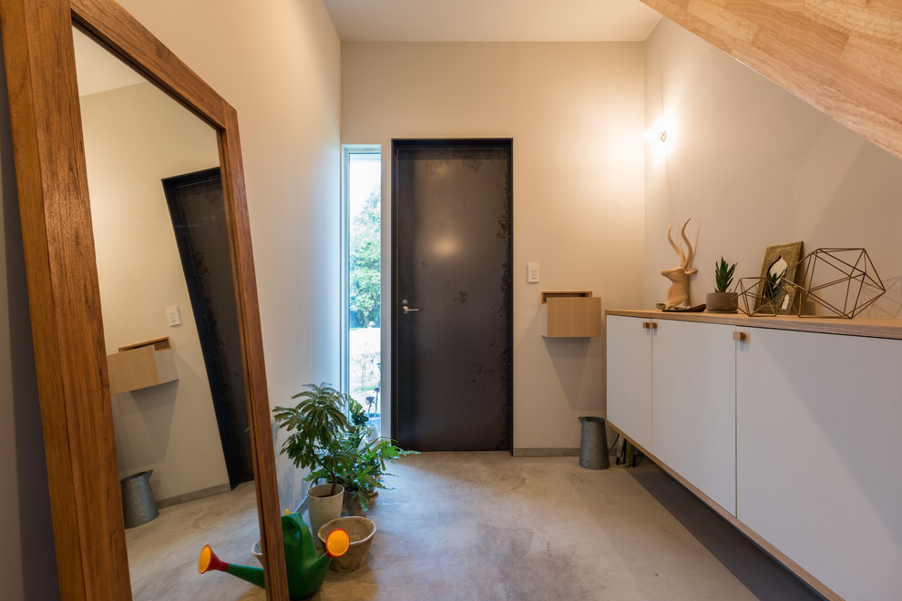 Photo of a contemporary entryway in Other with white walls, concrete floors, a single front door, a black front door and grey floor.
