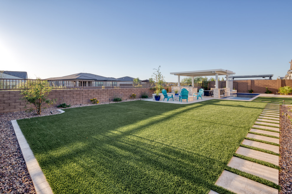 Large modern backyard rectangular natural pool in Phoenix with a water feature and concrete pavers.