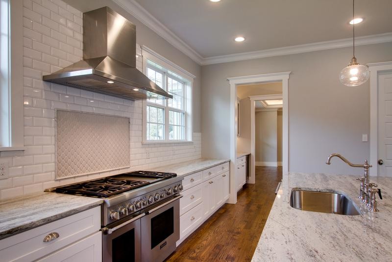 Inspiration for a large transitional u-shaped medium tone wood floor open concept kitchen remodel in Dallas with a drop-in sink, flat-panel cabinets, white cabinets, granite countertops, white backsplash, subway tile backsplash, stainless steel appliances and an island