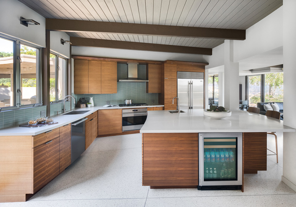 Exemple d'une cuisine ouverte blanche et bois rétro en L et bois clair avec une crédence bleue, un électroménager en acier inoxydable, un sol en terrazzo, îlot et un plan de travail blanc.