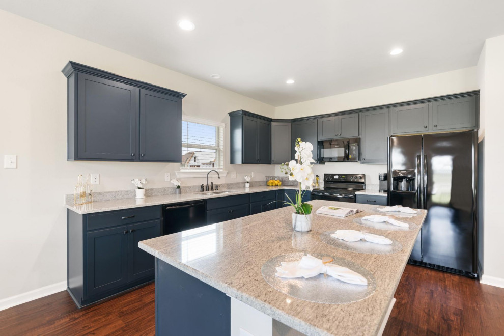 Exempel på ett mellanstort klassiskt vit vitt kök och matrum, med blå skåp, granitbänkskiva, svarta vitvaror, mörkt trägolv, en köksö och brunt golv