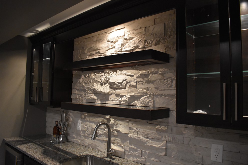 Inspiration for a mid-sized transitional single-wall wet bar in Indianapolis with an undermount sink, shaker cabinets, dark wood cabinets, granite benchtops, grey splashback and vinyl floors.