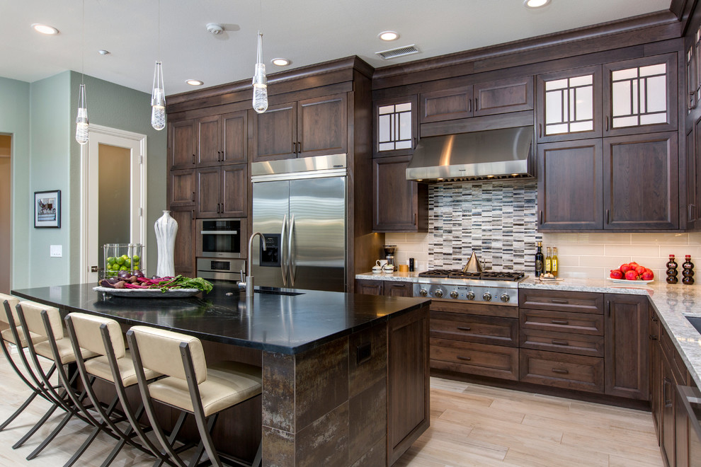 Open concept kitchen - huge transitional l-shaped porcelain tile open concept kitchen idea in Tampa with a single-bowl sink, recessed-panel cabinets, dark wood cabinets, soapstone countertops, beige backsplash, glass sheet backsplash, stainless steel appliances and an island