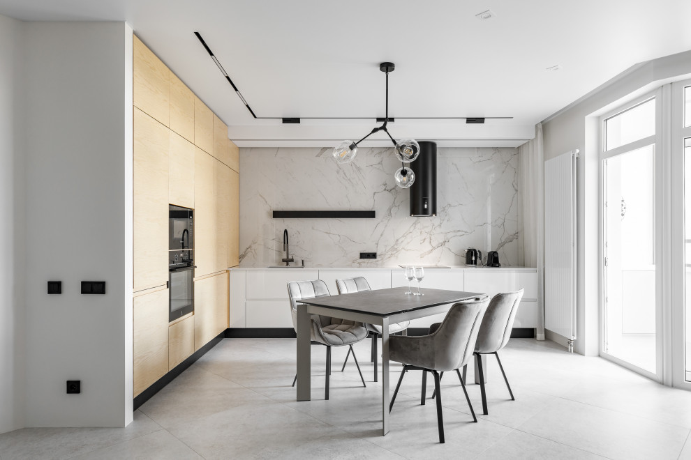 Mid-sized contemporary l-shaped open plan kitchen in Saint Petersburg with an undermount sink, flat-panel cabinets, white cabinets, white splashback, black appliances, no island, white floor and white benchtop.