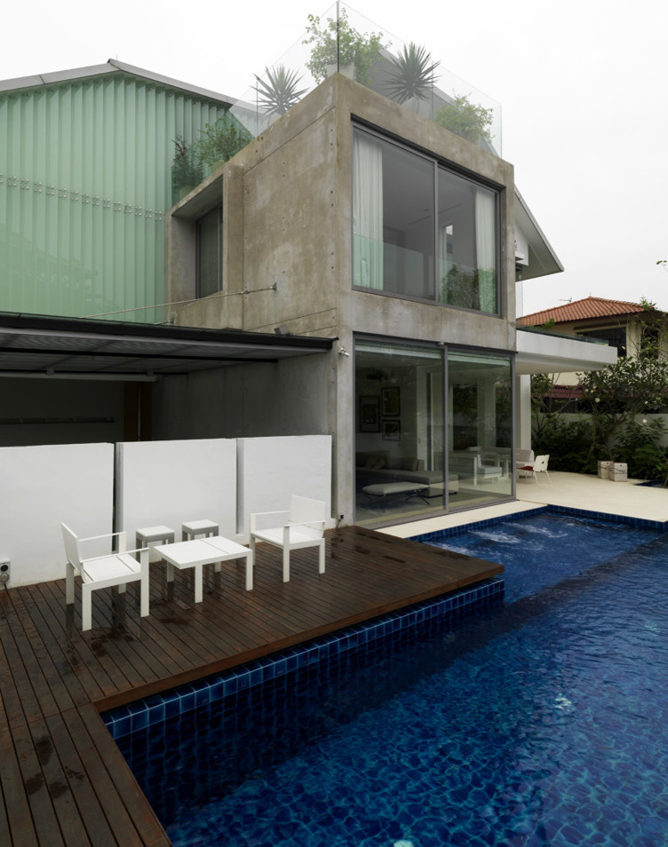 Photo of a mid-sized contemporary front yard custom-shaped pool in Singapore with a pool house and decking.