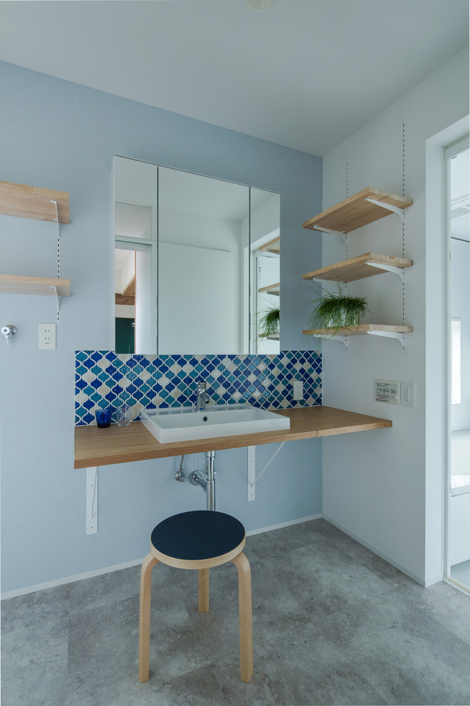 Photo of an industrial powder room in Other with blue walls, concrete floors, a vessel sink, wood benchtops, grey floor and brown benchtops.