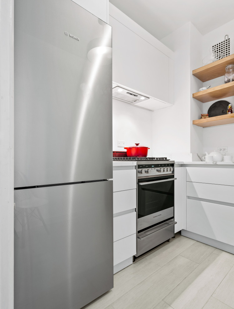 Mid-sized transitional l-shaped light wood floor enclosed kitchen photo in Chicago with an undermount sink, flat-panel cabinets, white cabinets, marble countertops, white backsplash, subway tile backsplash, stainless steel appliances, no island and white countertops