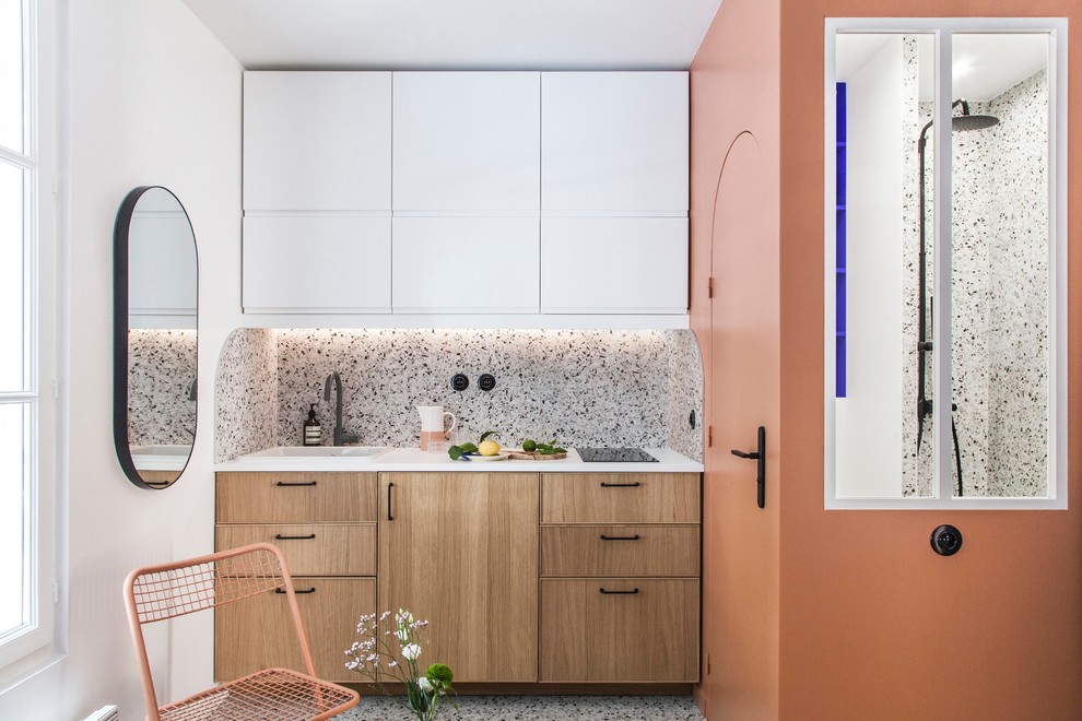 Photo of a small modern single-wall open plan kitchen in Paris with a single-bowl sink, beaded inset cabinets, light wood cabinets, laminate benchtops, multi-coloured splashback, ceramic splashback, panelled appliances, terrazzo floors, multi-coloured floor and white benchtop.