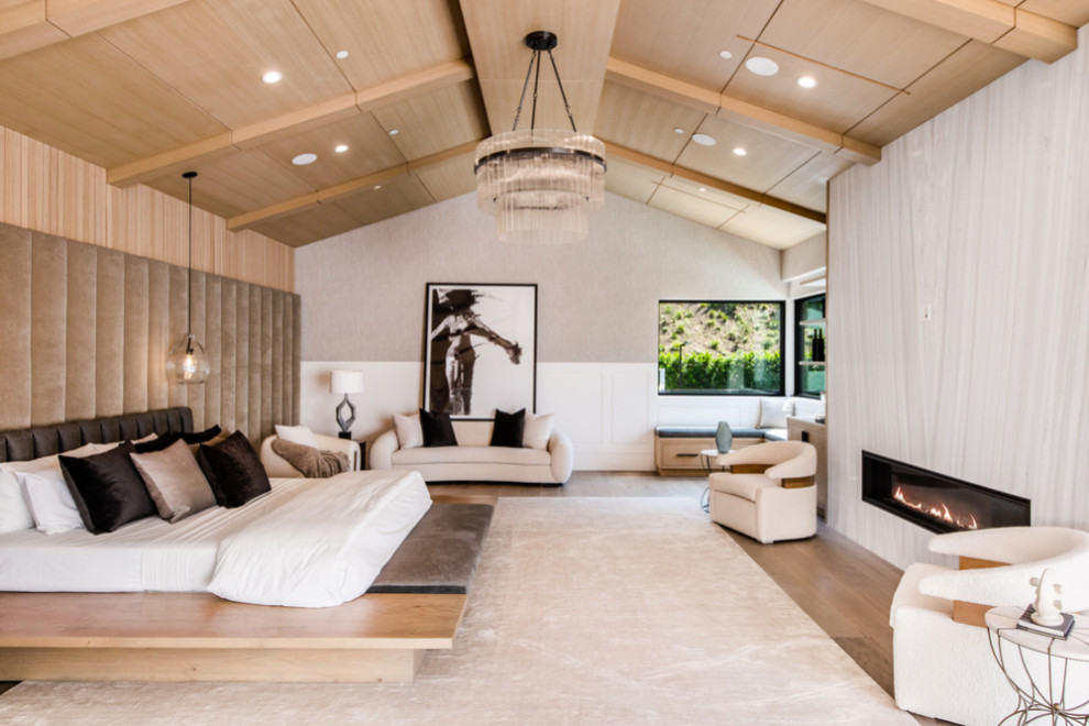 This is an example of a contemporary master bedroom in Los Angeles with a ribbon fireplace, a stone fireplace surround, timber and wood walls.