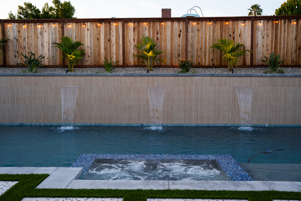 Пример оригинального дизайна: большой естественный, прямоугольный ландшафтный бассейн на заднем дворе в стиле модернизм с мощением тротуарной плиткой
