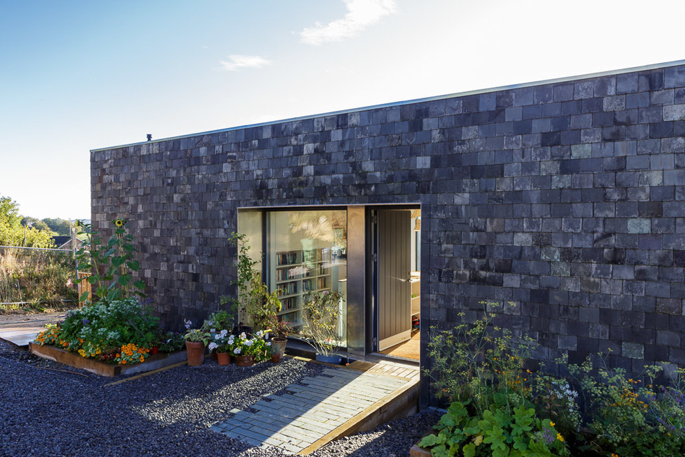 Inspiration for a mid-sized contemporary two-storey exterior in Gloucestershire with mixed siding and a flat roof.