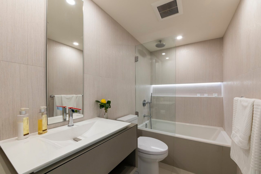 This is an example of a mid-sized contemporary 3/4 bathroom in Vancouver with grey cabinets, a drop-in tub, a curbless shower, a two-piece toilet, beige tile, cement tile, beige walls, a trough sink, beige floor, a hinged shower door, a single vanity, flat-panel cabinets, vaulted, a floating vanity, wood benchtops and brown benchtops.