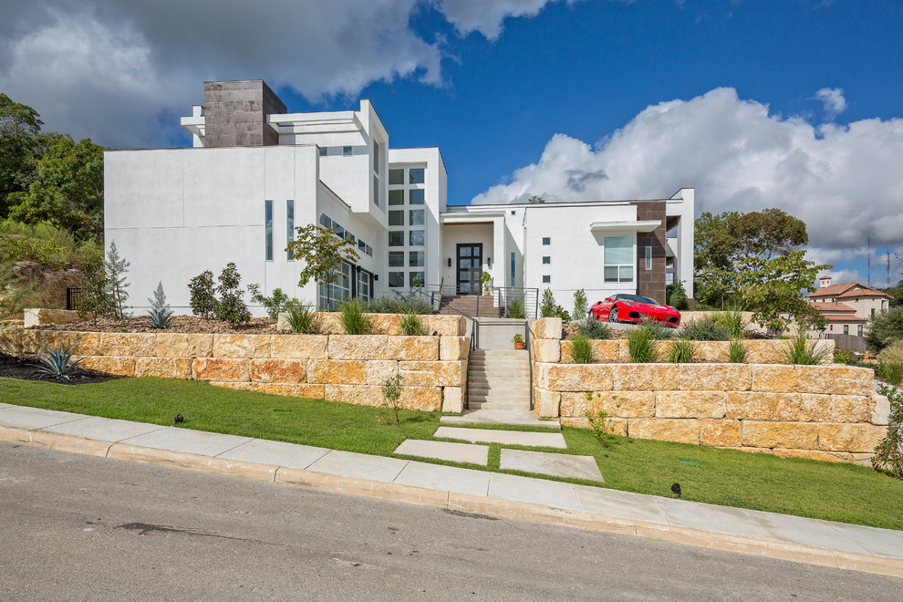 This is an example of a large contemporary two-storey white exterior in Austin with a flat roof.