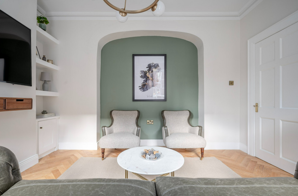 Immagine di un soggiorno chic di medie dimensioni e chiuso con sala formale, pareti verdi, pavimento in legno massello medio, TV a parete e pavimento marrone