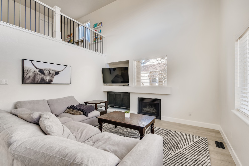 Modern inredning av ett stort allrum på loftet, med vita väggar, vinylgolv, en standard öppen spis, en väggmonterad TV och grått golv