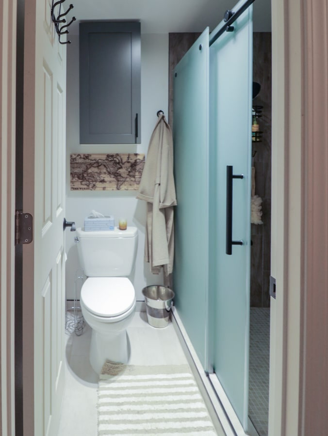 This is an example of a mid-sized modern master bathroom in Seattle with shaker cabinets, light wood cabinets, an undermount tub, a shower/bathtub combo, a bidet, white tile, marble, white walls, porcelain floors, an undermount sink, marble benchtops, brown floor, a sliding shower screen, white benchtops, an enclosed toilet, a single vanity, a built-in vanity, timber and planked wall panelling.