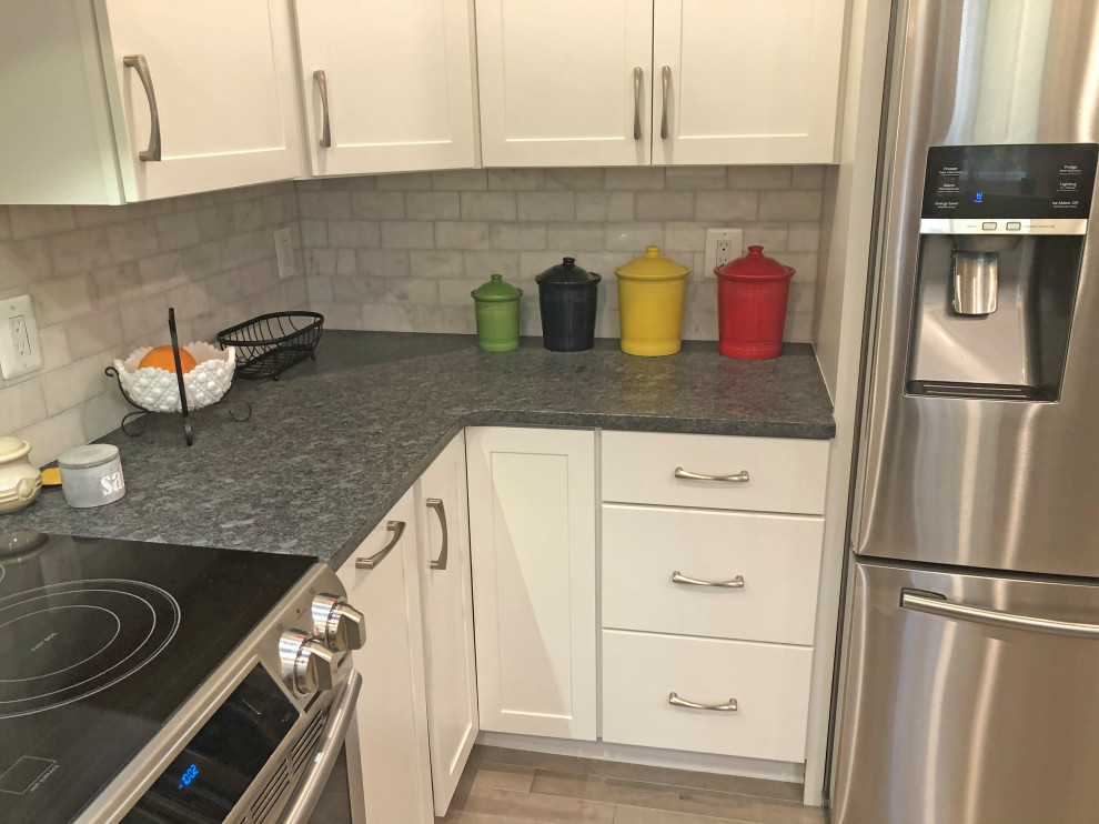This is an example of a small transitional u-shaped eat-in kitchen in Baltimore with a double-bowl sink, shaker cabinets, white cabinets, granite benchtops, grey splashback, marble splashback, stainless steel appliances, light hardwood floors, a peninsula, beige floor and grey benchtop.