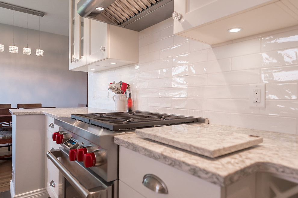 Inspiration for a mid-sized transitional galley porcelain tile eat-in kitchen remodel in Vancouver with a farmhouse sink, shaker cabinets, white cabinets, quartz countertops, white backsplash, subway tile backsplash, stainless steel appliances and no island