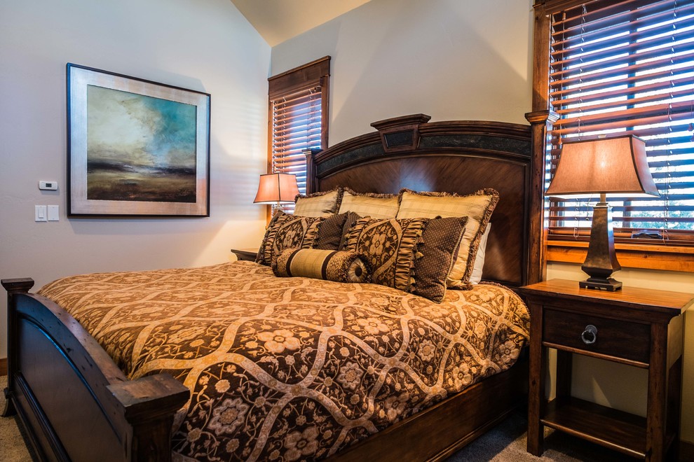 Example of a mid-sized mountain style guest carpeted bedroom design with beige walls, a corner fireplace and a stone fireplace