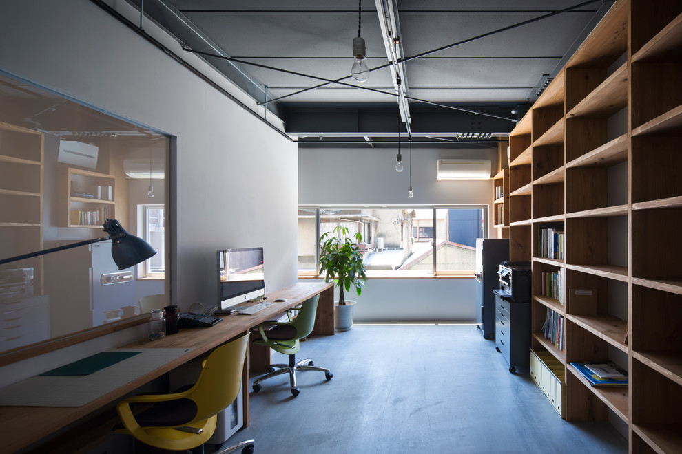 Photo of an industrial home office in Osaka with grey walls, concrete floors, grey floor and a built-in desk.