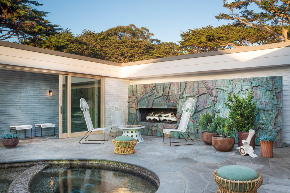 Inspiration for a midcentury courtyard patio in Other with with fireplace, natural stone pavers and no cover.