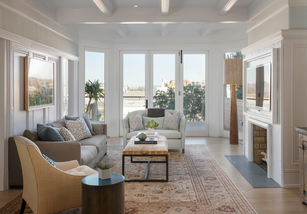 This is an example of a transitional living room in San Francisco with white walls, light hardwood floors, a standard fireplace and a wall-mounted tv.