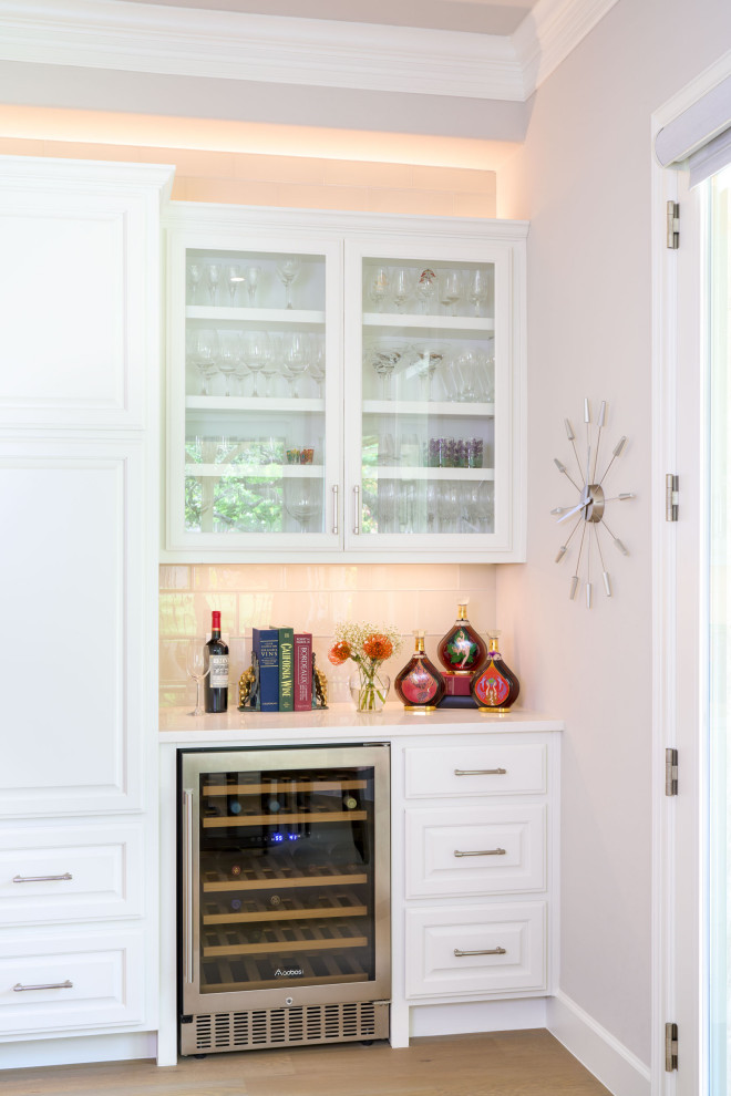 Inspiration for a large transitional l-shaped light wood floor open concept kitchen remodel in Austin with white cabinets, white backsplash, white countertops, an undermount sink, raised-panel cabinets, stainless steel appliances and an island