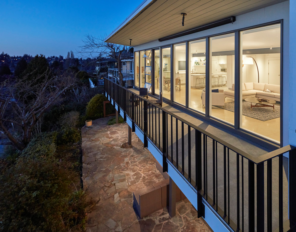 This is an example of a retro back first floor metal railing terrace in Seattle with a roof extension.