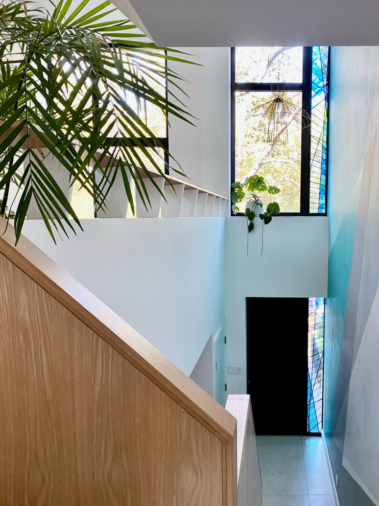 Idée de décoration pour une entrée minimaliste avec un mur blanc, un sol en terrazzo, une porte simple et une porte noire.