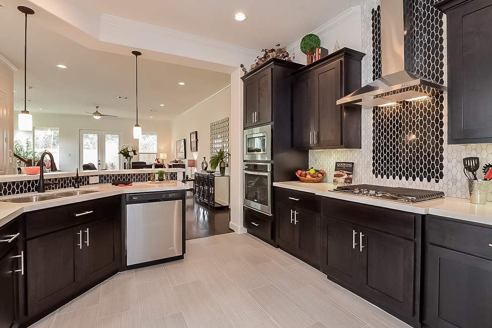 This is an example of a transitional kitchen in Houston with a double-bowl sink, shaker cabinets, dark wood cabinets, white splashback, stainless steel appliances, light hardwood floors and with island.