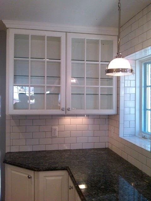 Example of a mid-sized transitional galley concrete floor open concept kitchen design in St Louis with a farmhouse sink, shaker cabinets, medium tone wood cabinets, granite countertops, white backsplash, ceramic backsplash, stainless steel appliances and an island