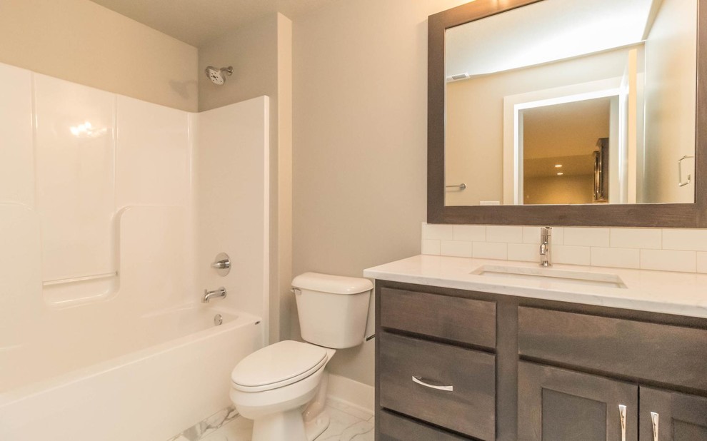 Alcove bathtub - mid-sized transitional kids' white tile and subway tile marble floor alcove bathtub idea with shaker cabinets, dark wood cabinets, a two-piece toilet, gray walls, an undermount sink and marble countertops