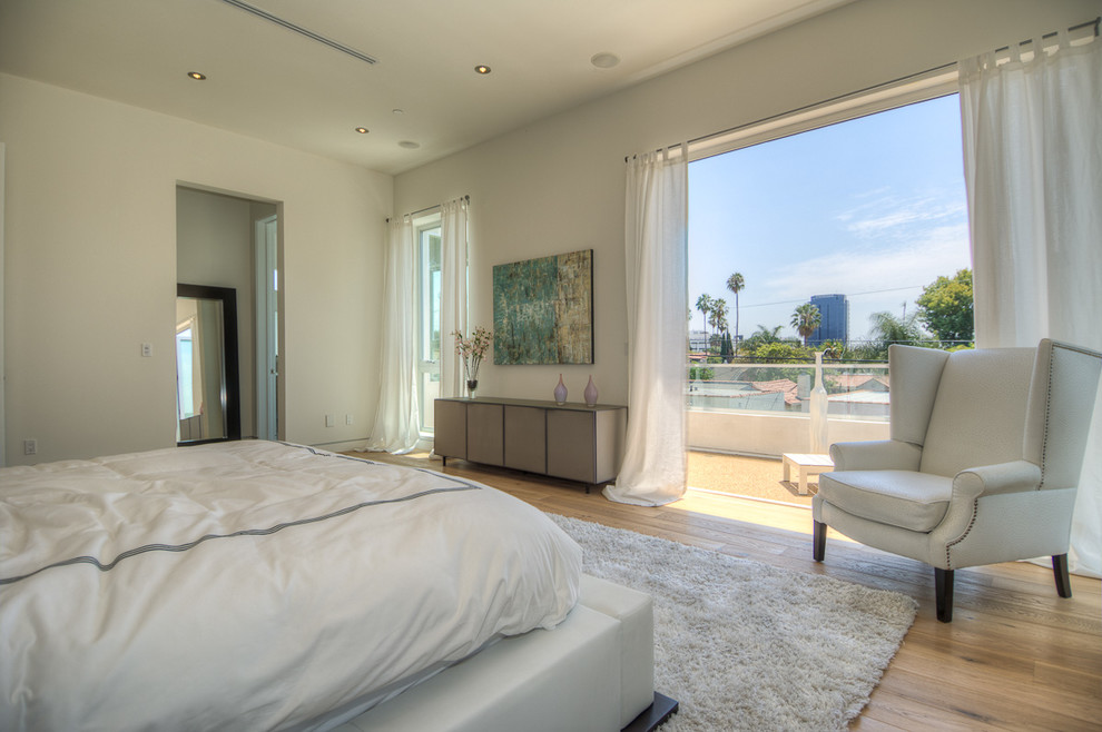 Large contemporary master bedroom in Los Angeles with white walls, light hardwood floors and no fireplace.