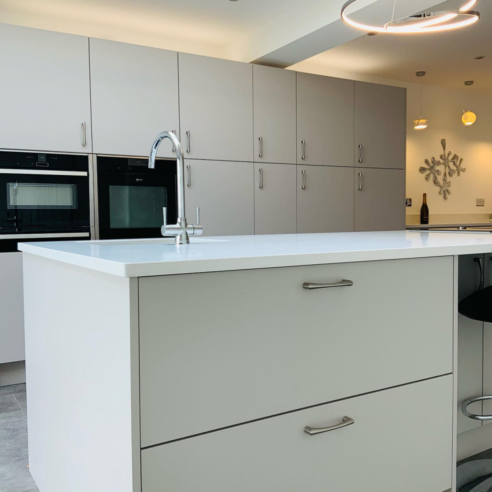 Modelo de cocina minimalista grande abierta con armarios con paneles lisos, encimera de cuarcita, electrodomésticos con paneles, una isla y encimeras blancas