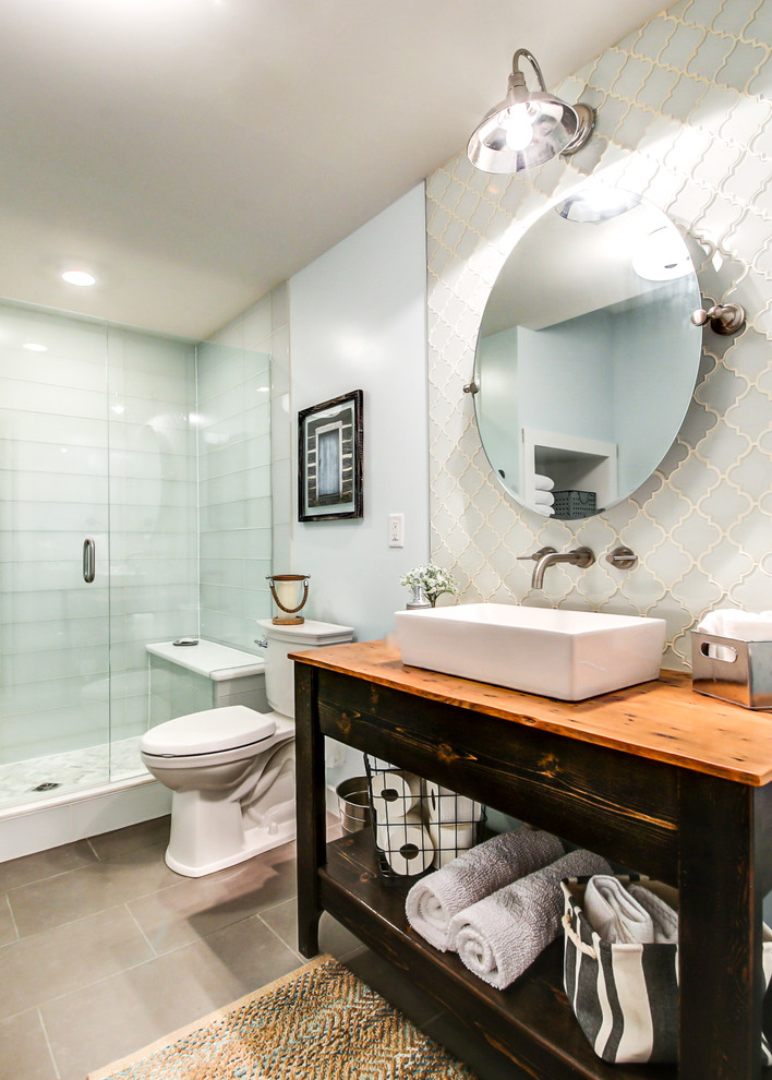 Mid-sized eclectic master bathroom in Dallas with furniture-like cabinets, distressed cabinets, a freestanding tub, an alcove shower, a two-piece toilet, blue tile, glass tile, blue walls, porcelain floors, a vessel sink, wood benchtops, grey floor, a hinged shower door and brown benchtops.