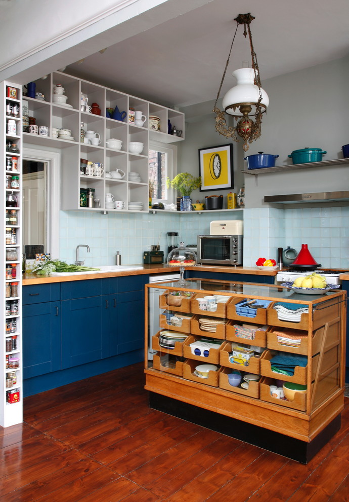 Photo of an eclectic l-shaped kitchen in London with a drop-in sink, shaker cabinets, blue cabinets, wood benchtops, blue splashback, ceramic splashback, dark hardwood floors and with island.