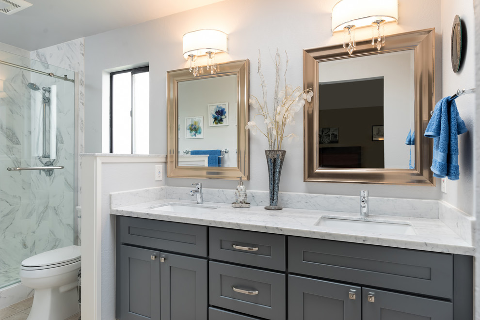 Inspiration for a large transitional master bathroom in Other with shaker cabinets, grey cabinets, an alcove shower, a two-piece toilet, white tile, marble, beige walls, travertine floors, an undermount sink, quartzite benchtops, beige floor, a sliding shower screen and white benchtops.