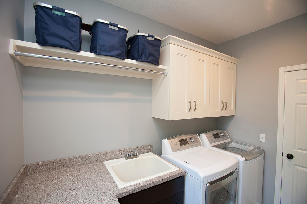 Design ideas for a mid-sized contemporary galley utility room in Minneapolis with a drop-in sink, recessed-panel cabinets, white cabinets, quartzite benchtops, grey walls, porcelain floors and a side-by-side washer and dryer.
