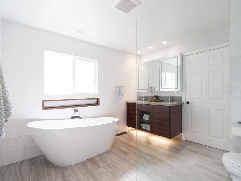 Inspiration for a large transitional master white tile and ceramic tile porcelain tile, gray floor and double-sink freestanding bathtub remodel with flat-panel cabinets, dark wood cabinets, a one-piece toilet, white walls, an undermount sink, quartz countertops, gray countertops, a niche and a floating vanity