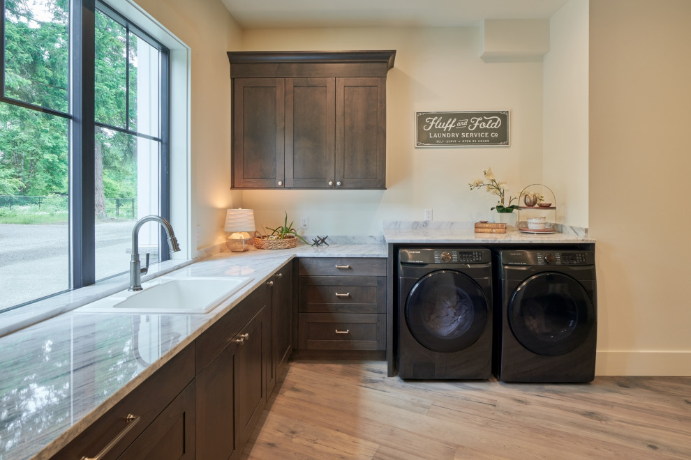 Photo of a large farmhouse u-shaped utility room in Seattle with a submerged sink, recessed-panel cabinets, brown cabinets, wood worktops, black splashback, ceramic splashback, white walls, light hardwood flooring, a side by side washer and dryer, brown floors, black worktops and tongue and groove walls.