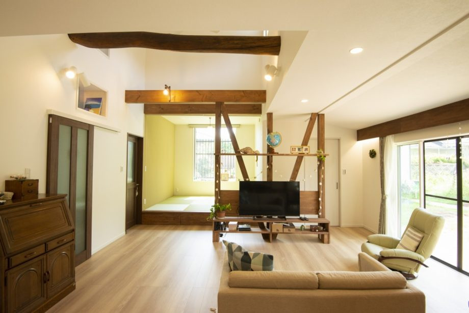 This is an example of a rural living room in Other with plywood flooring, brown floors, exposed beams and wallpapered walls.