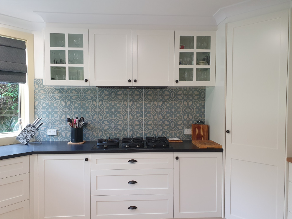 Inspiration for a mid-sized timeless u-shaped ceramic tile eat-in kitchen remodel in Sydney with shaker cabinets, white cabinets, laminate countertops, blue backsplash, porcelain backsplash and black countertops