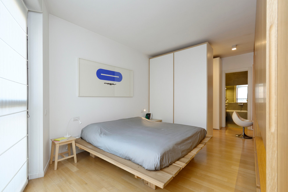 Kleines Modernes Hauptschlafzimmer mit weißer Wandfarbe und hellem Holzboden in Mailand