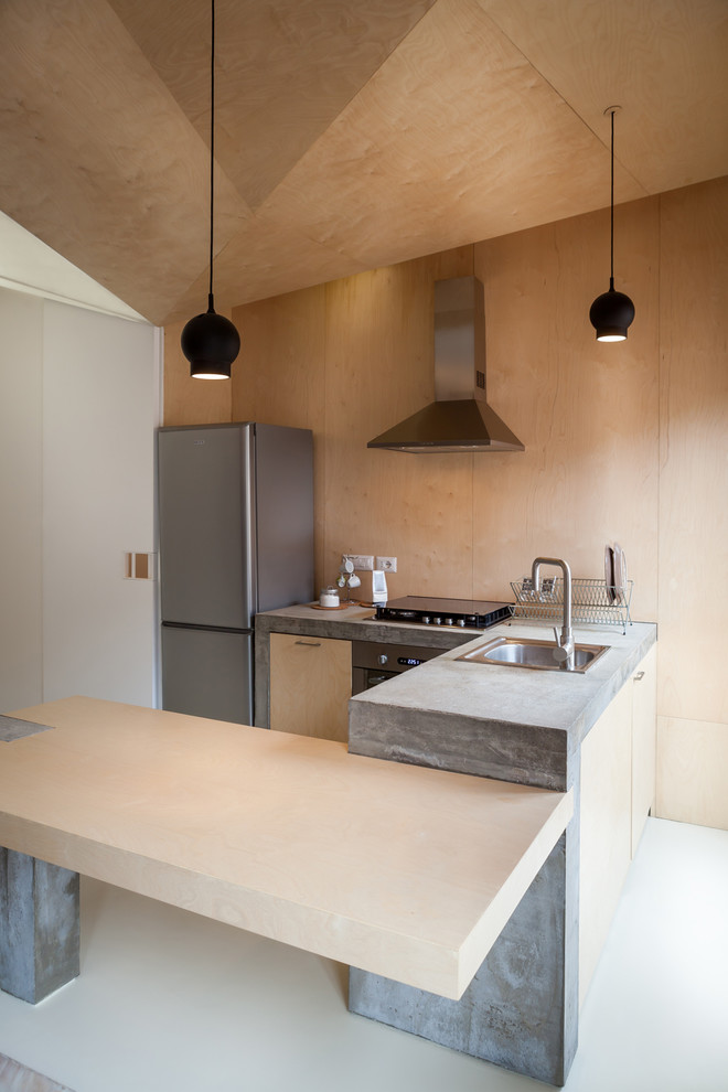 Photo of a mid-sized contemporary u-shaped eat-in kitchen in Turin with a drop-in sink, flat-panel cabinets, light wood cabinets, concrete benchtops, beige splashback and stainless steel appliances.