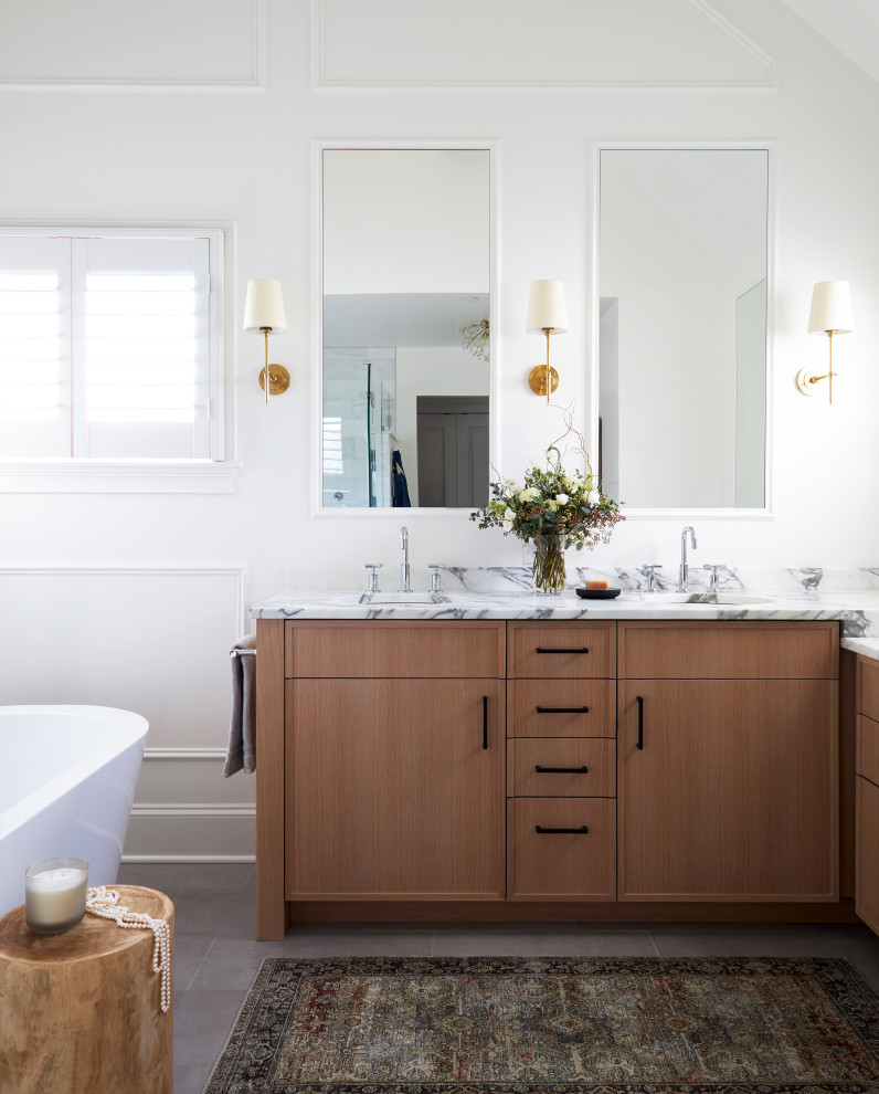 Пример оригинального дизайна: большая главная ванная комната в белых тонах с отделкой деревом в стиле модернизм с плоскими фасадами, светлыми деревянными фасадами, отдельно стоящей ванной, двойным душем, унитазом-моноблоком, разноцветной плиткой, мраморной плиткой, белыми стенами, полом из керамогранита, накладной раковиной, мраморной столешницей, серым полом, душем с распашными дверями, разноцветной столешницей, сиденьем для душа, тумбой под две раковины, встроенной тумбой и сводчатым потолком