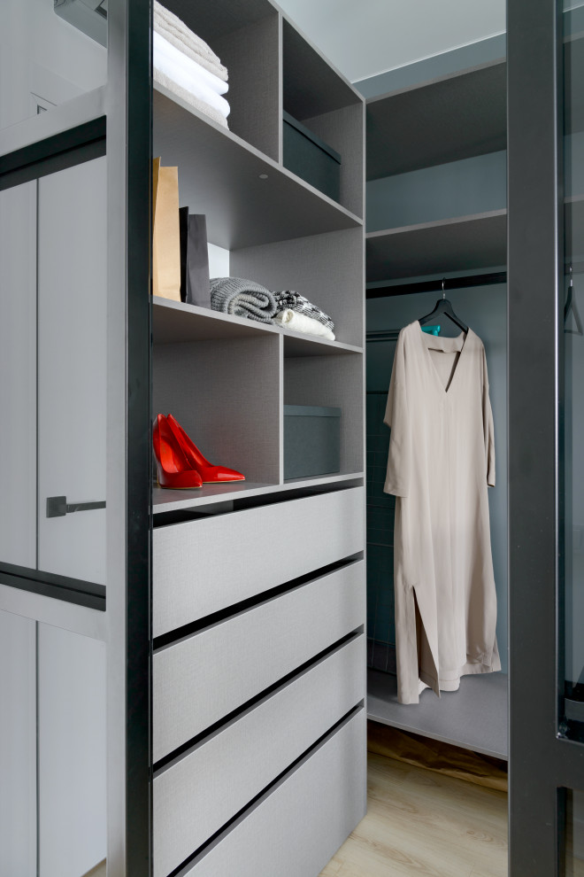 Photo of a mid-sized contemporary gender-neutral walk-in wardrobe in Novosibirsk with flat-panel cabinets, grey cabinets, laminate floors and beige floor.