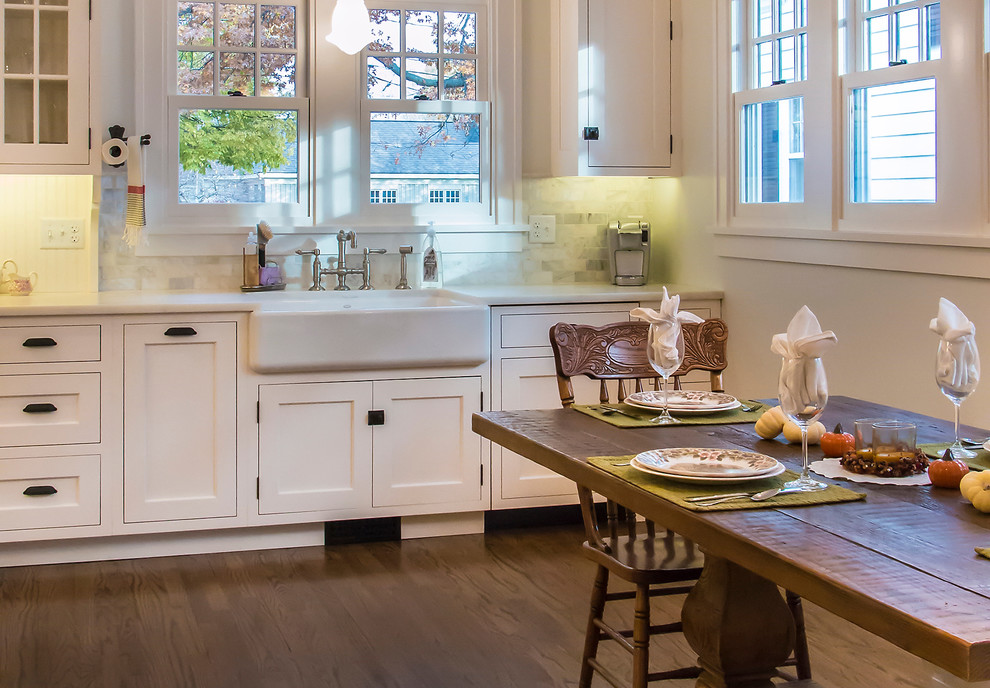 Large traditional l-shaped eat-in kitchen in Chicago with a farmhouse sink, flat-panel cabinets, white cabinets, marble benchtops, white splashback, stone tile splashback, panelled appliances, medium hardwood floors and with island.