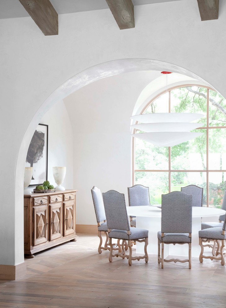 This is an example of a mediterranean dining room in Austin with white walls and medium hardwood floors.