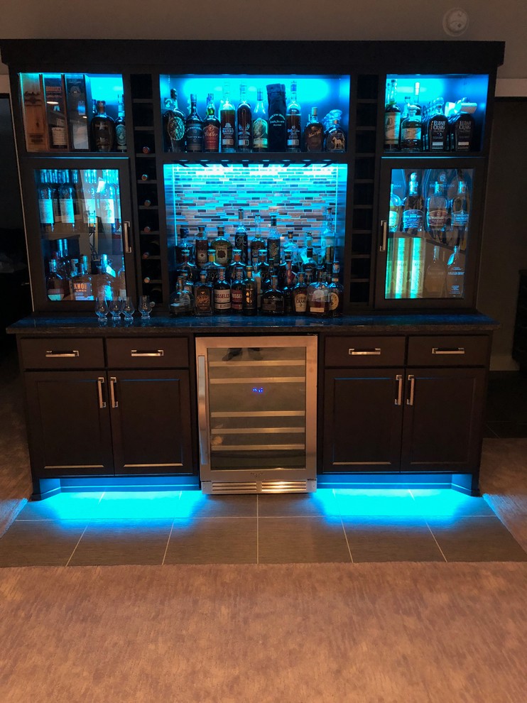 Mid-sized traditional single-wall home bar in Other with no sink, dark wood cabinets, granite benchtops, multi-coloured splashback, glass sheet splashback, vinyl floors, multi-coloured floor and multi-coloured benchtop.